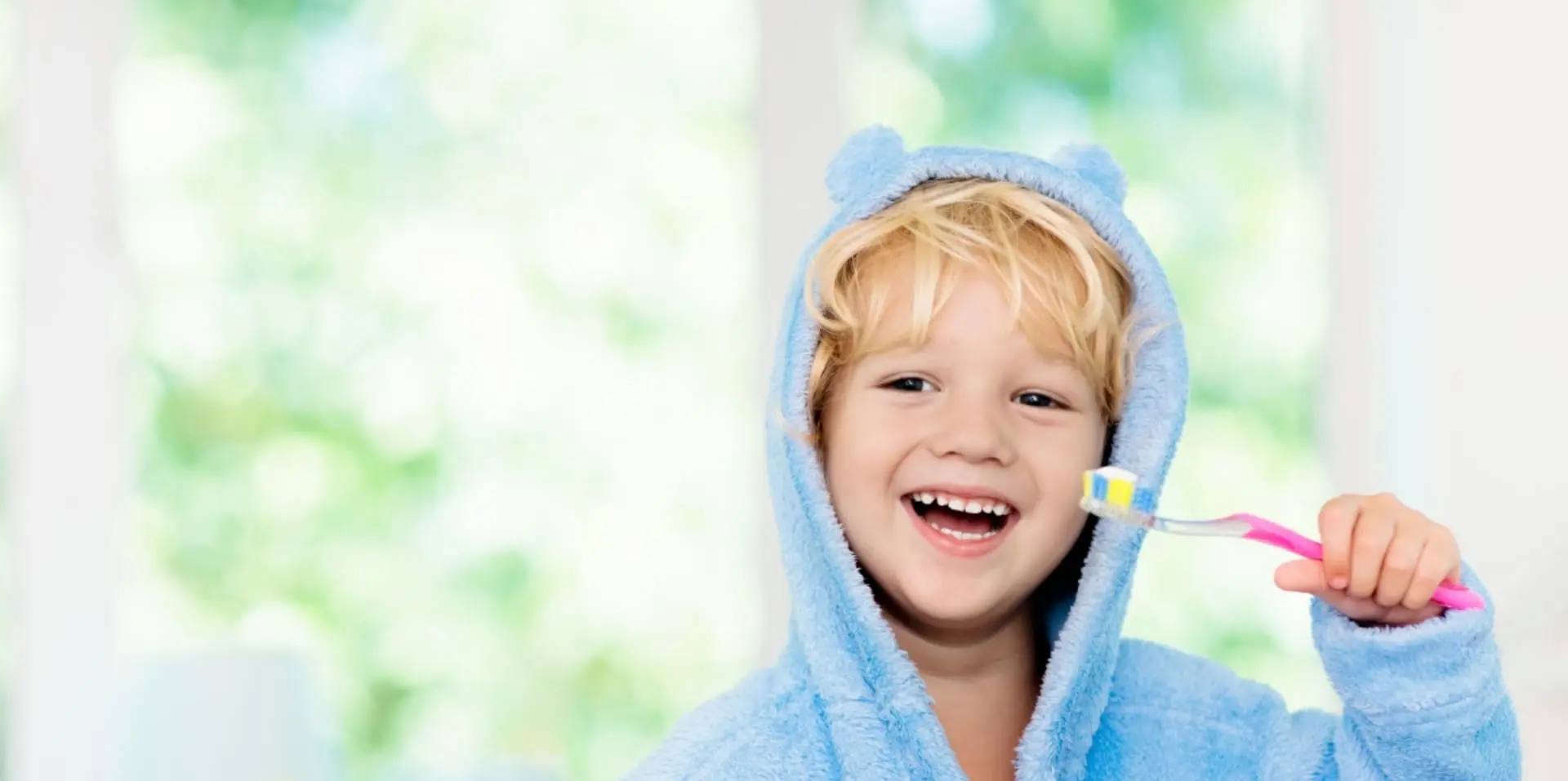 Wild Smiles Pediatric Dentistry - Young child smiling holding a tooth brush